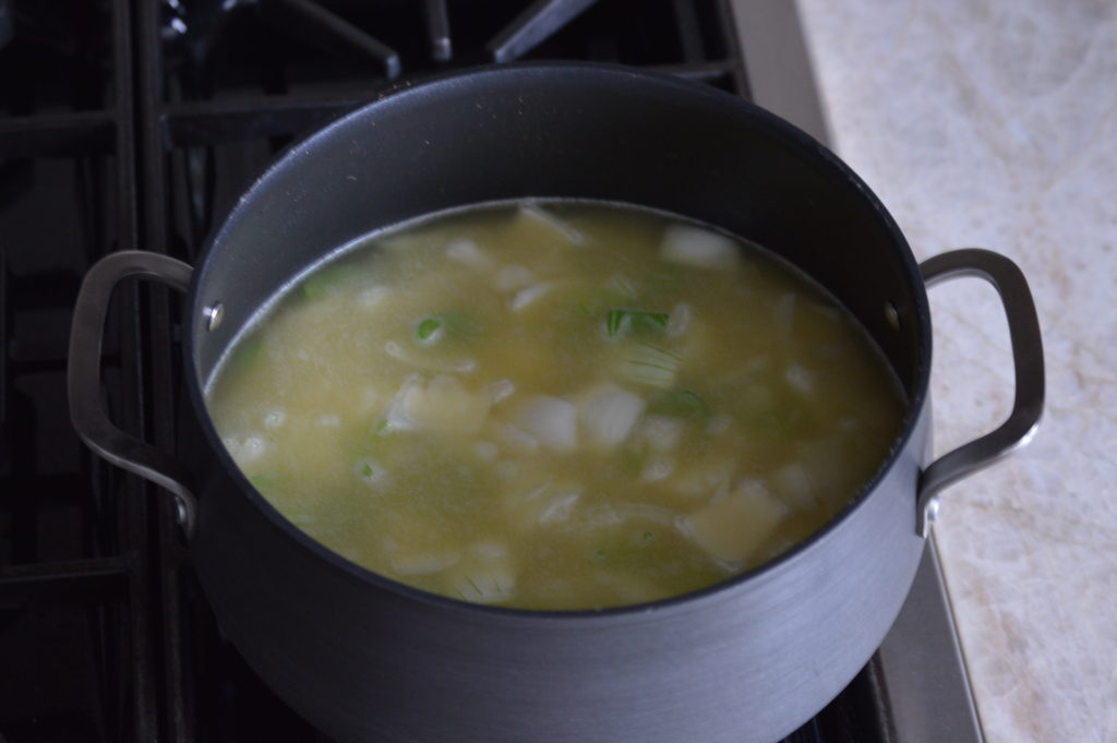 the pot filled with chicken stock, onion, celery and potato