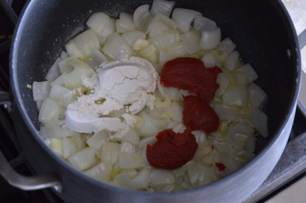 sauteing the onion and garlic then adding in the flour and tomato paste