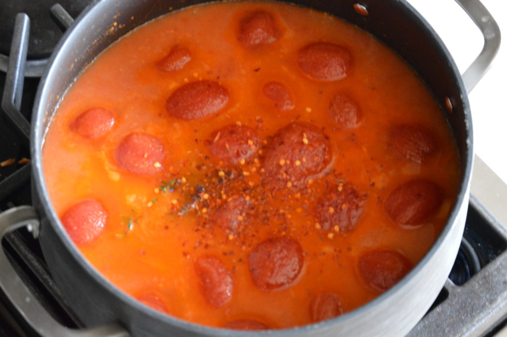 the chicken stock and tomatoes are added to the pot