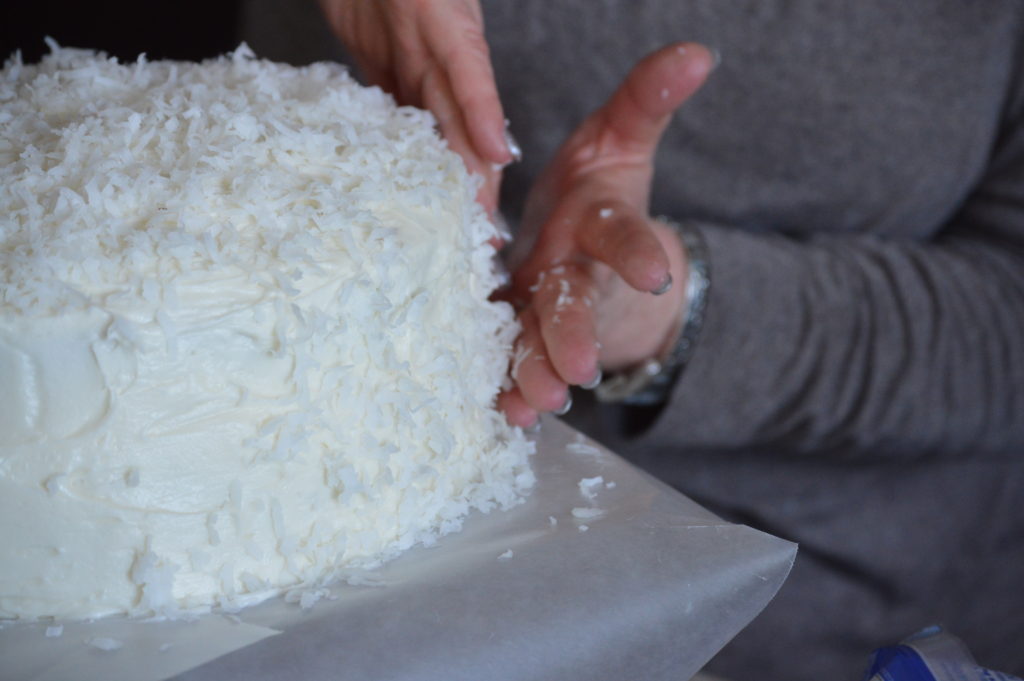 matting on the shaved coconiut onto the cake.