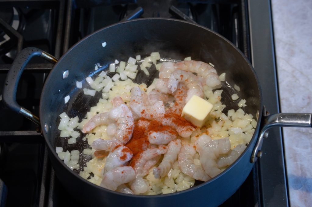 shrimp, spices, and butter being added to the pan.