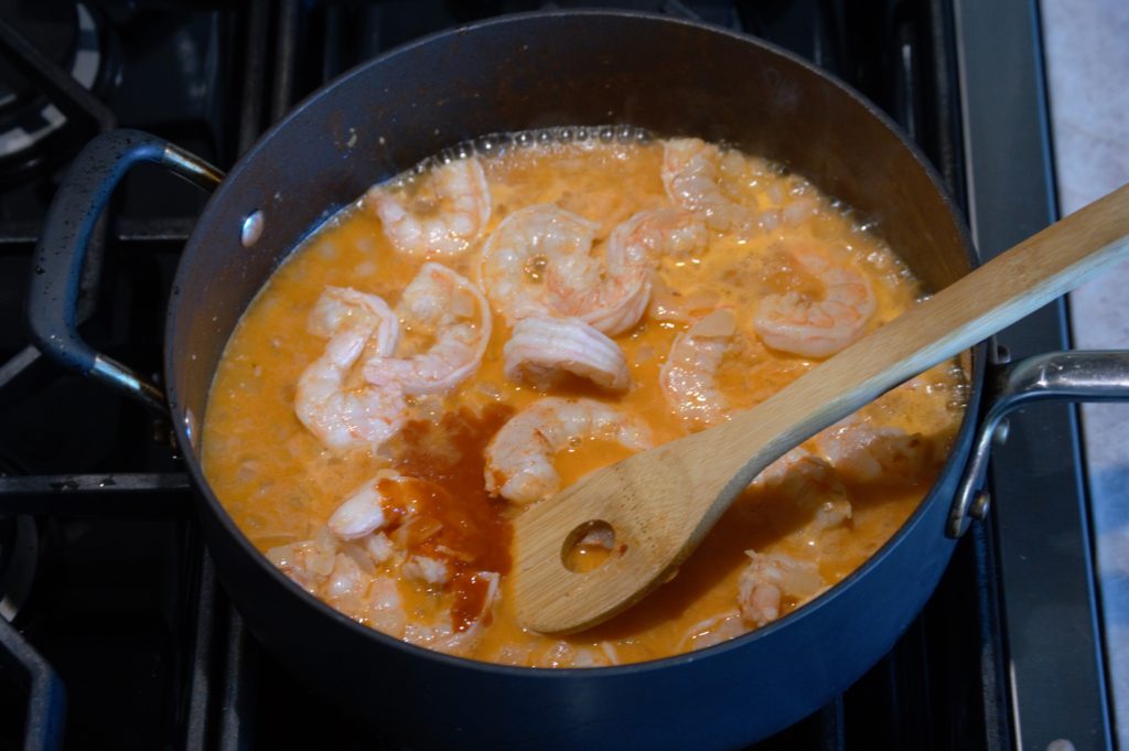 Wine, and hot sauce have been added to the pan. they begin to simmer.