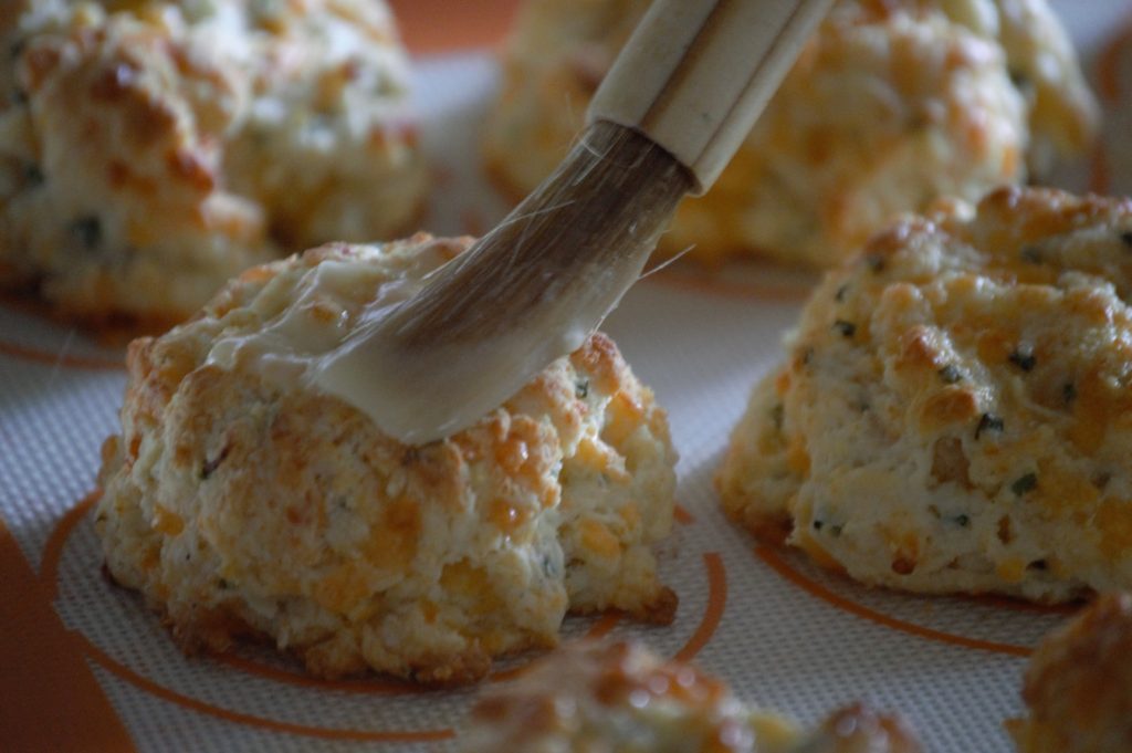 Cheddar chive biscuit being buttered