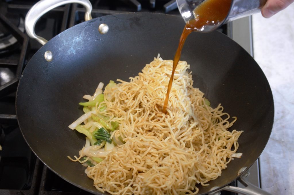 The noodles and sauce added to the wok