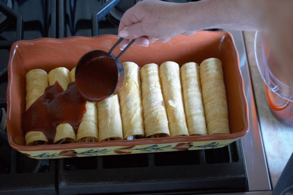 enchilada sauce being poured on top