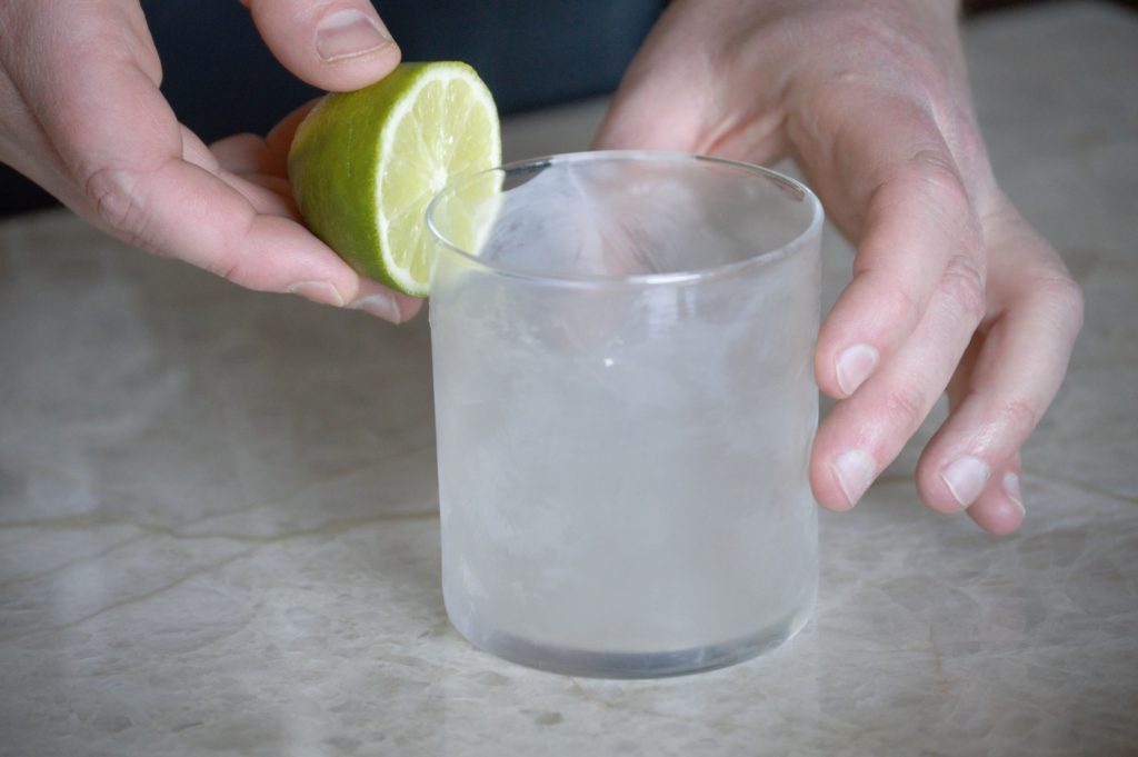 Applying lime juice to the outer rim of the glass