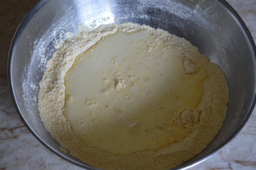 wet and dry southern corn bread ingredients added together in a bowl