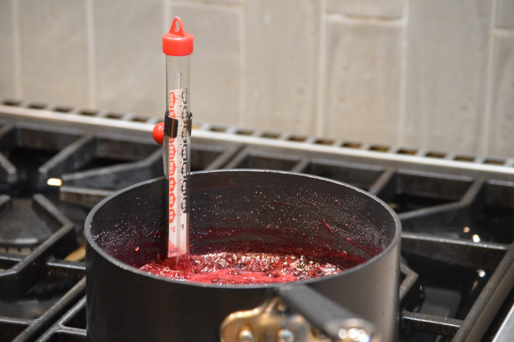 checking the four berry jam with a candy thermometer