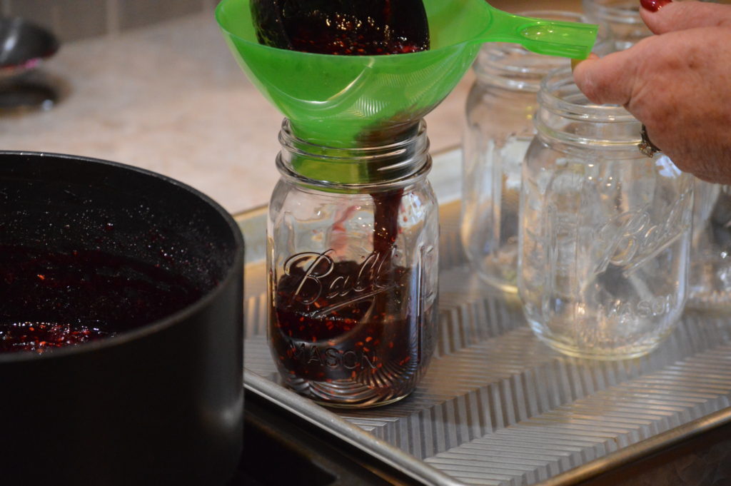 adding the four berry jam to the jars