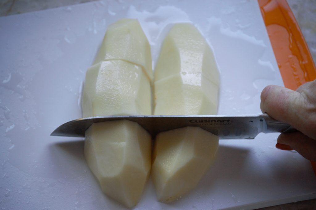 cutting up the peeled potatoes