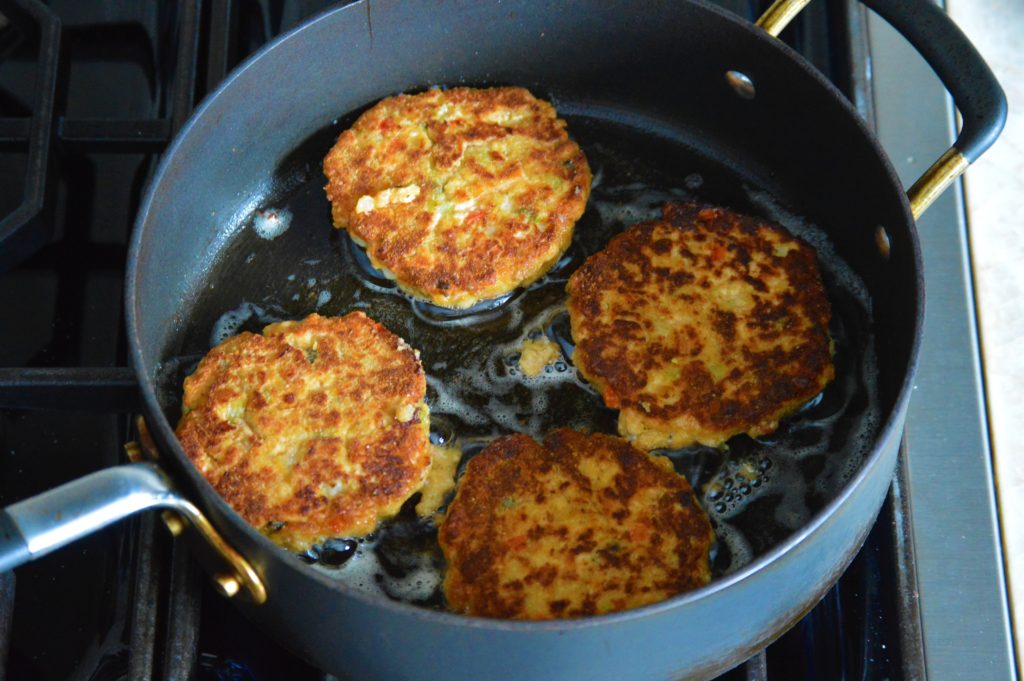 the salmon cakes flipped over and frying on the other sid