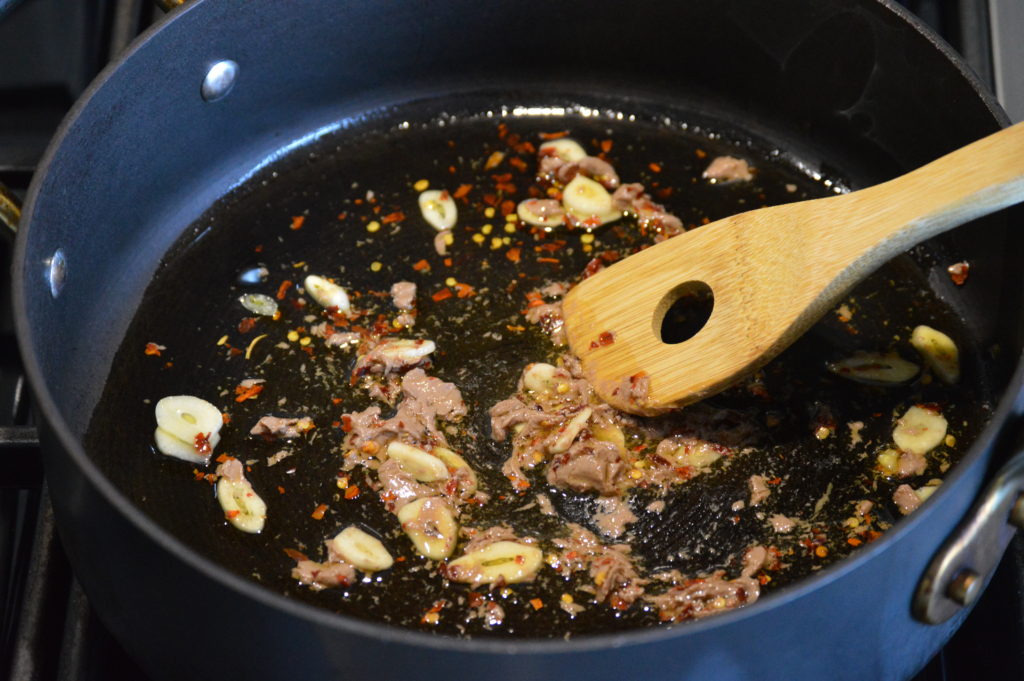 frying the garlic, chili pepper, and anchovies in a pan