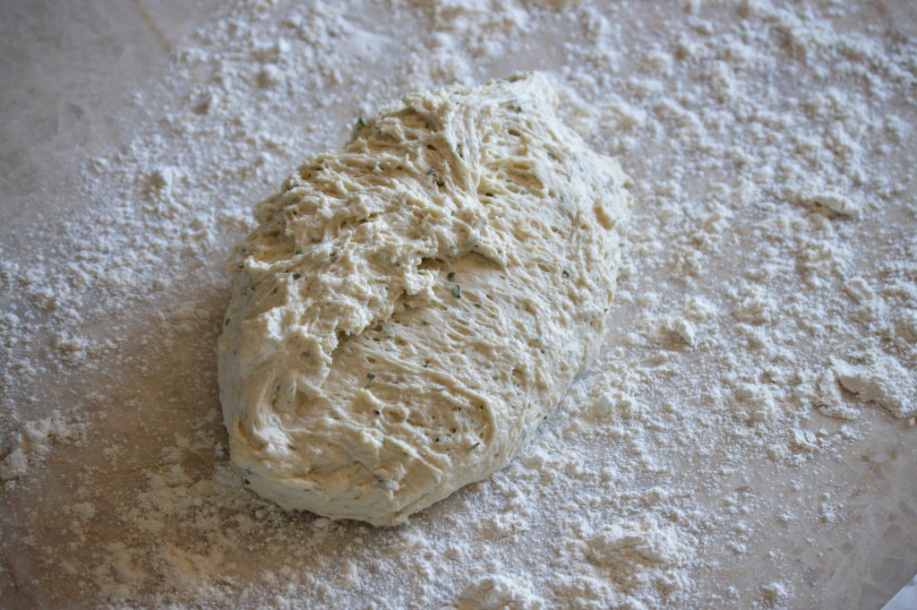 rolling the no-knead bread dough in flour