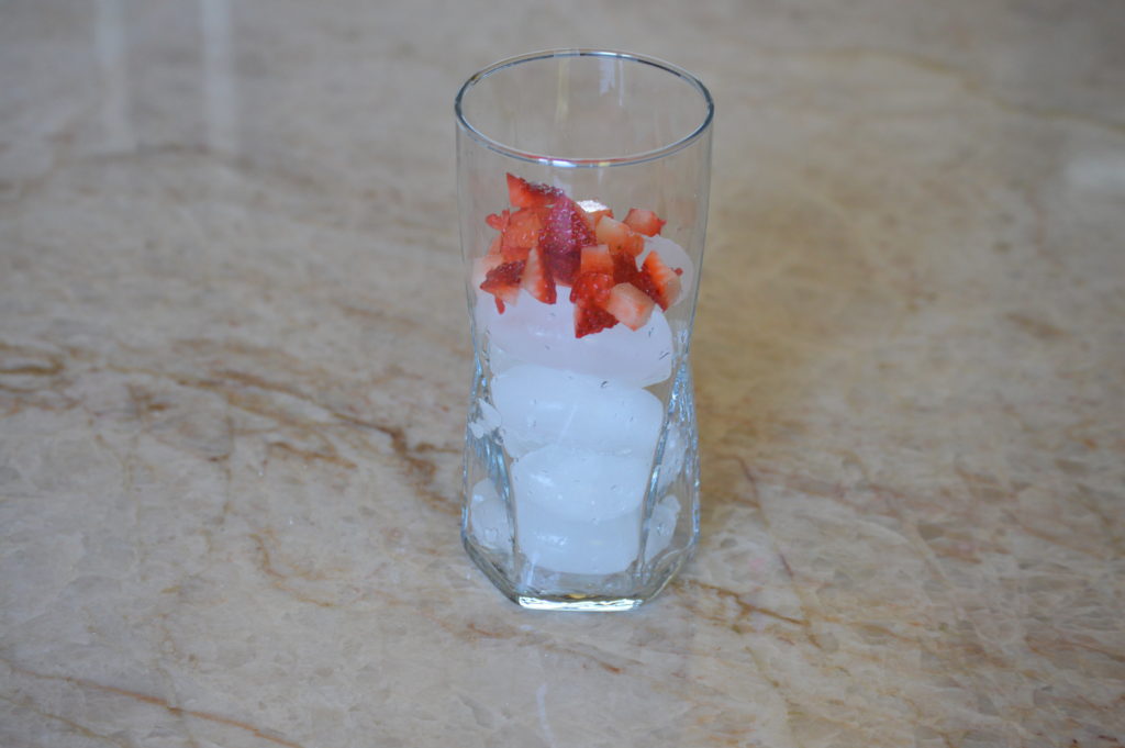 a glass filled with ice and diced strawberries