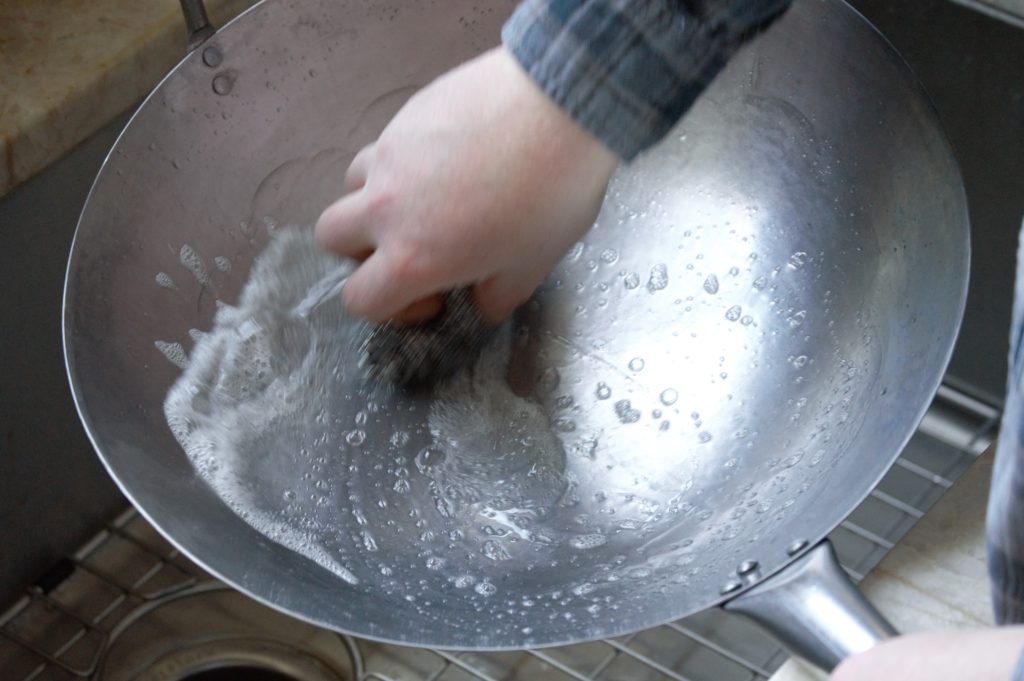 scrubbing the carbon steel wok clean