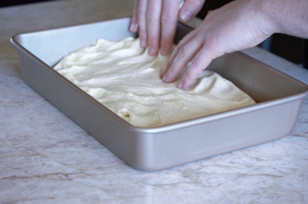 spreading the focaccia dough into a pan