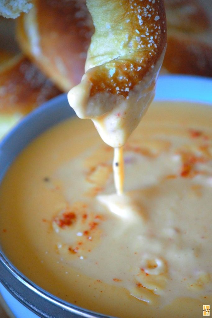 dipping a soft pretzel in the beer cheese dip