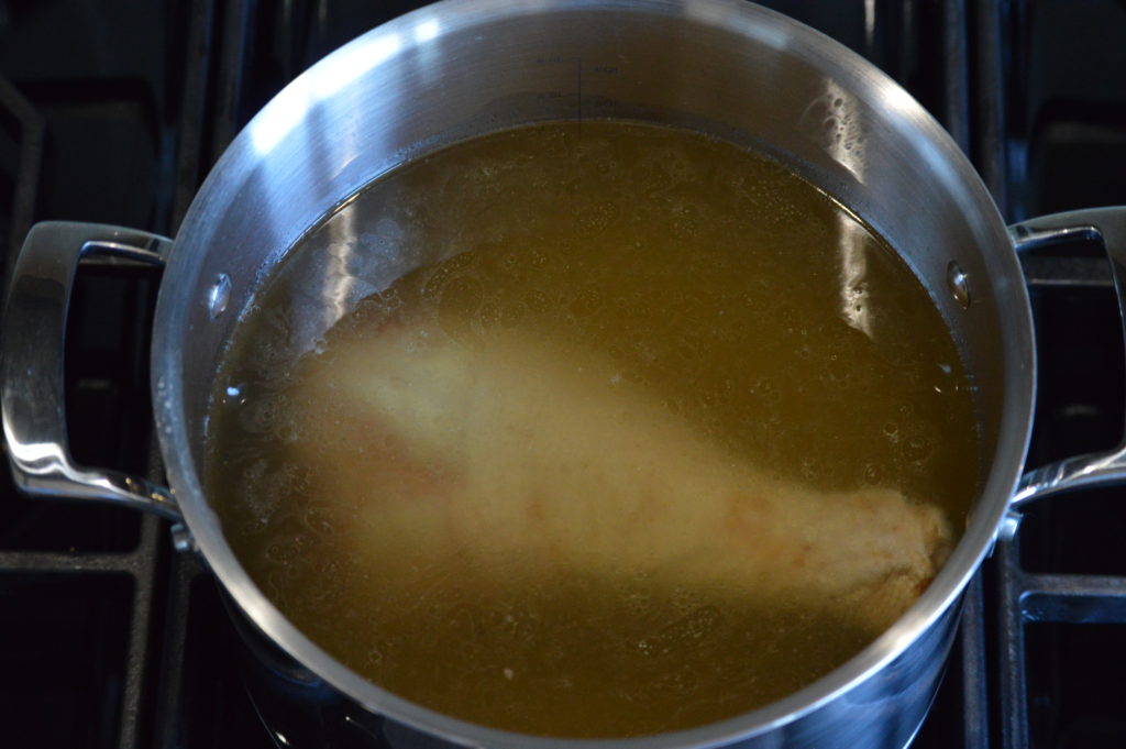 a smoke turkey leg along with chicken stock and water in a pot