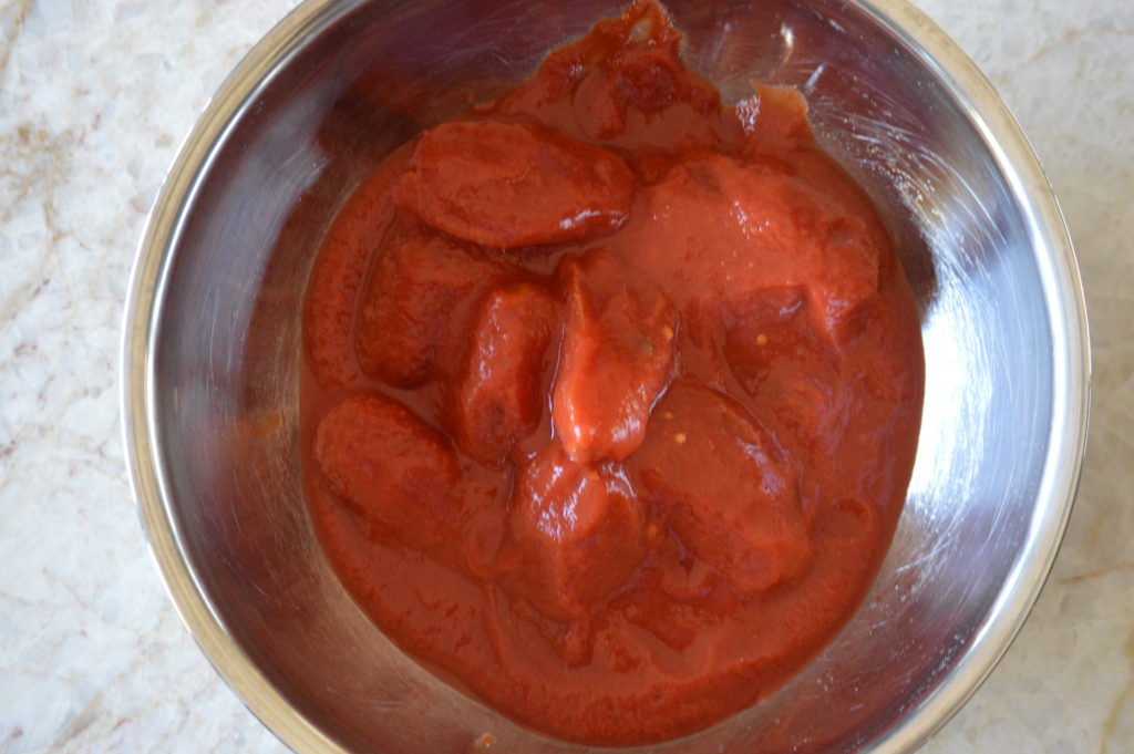 can of whole tomatoes in a mixing bowl