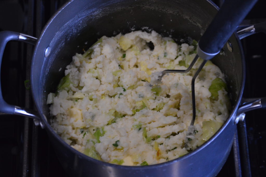 mashing the potatoes, cabbage, and green onions together