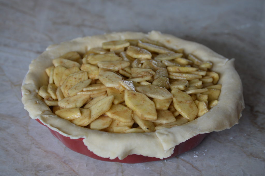 the first layer of pie crust is filled with the apple filling