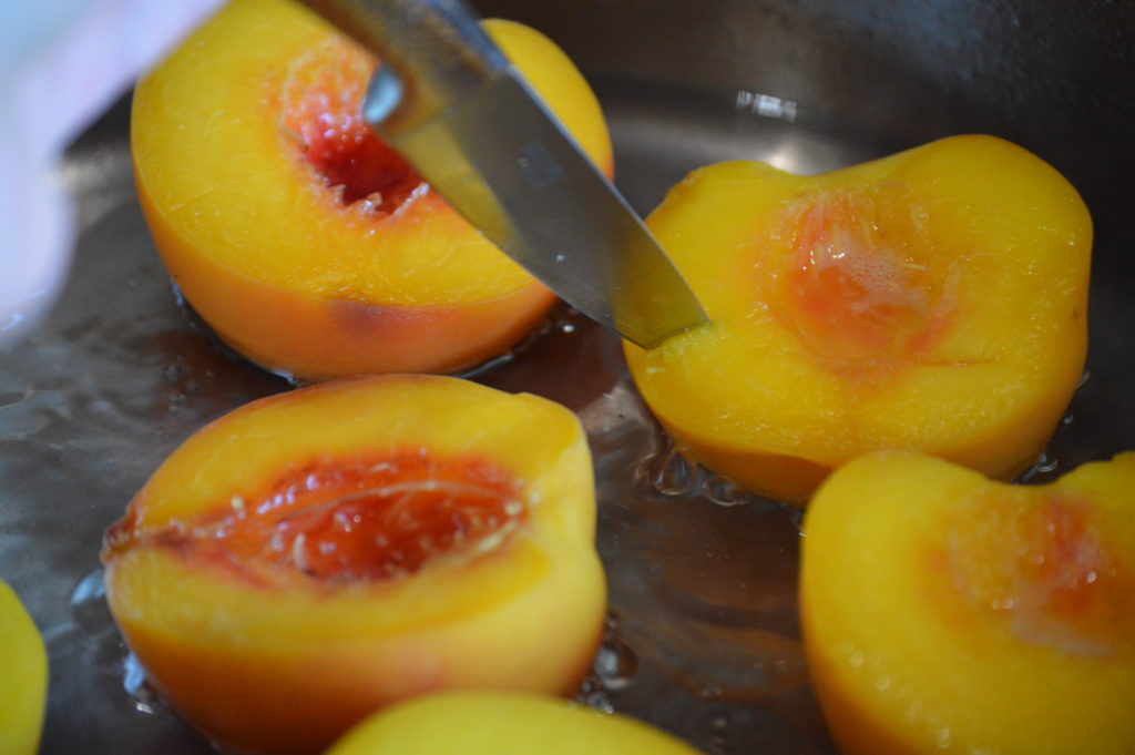 piercing the flesh of the peaches to see if they are done