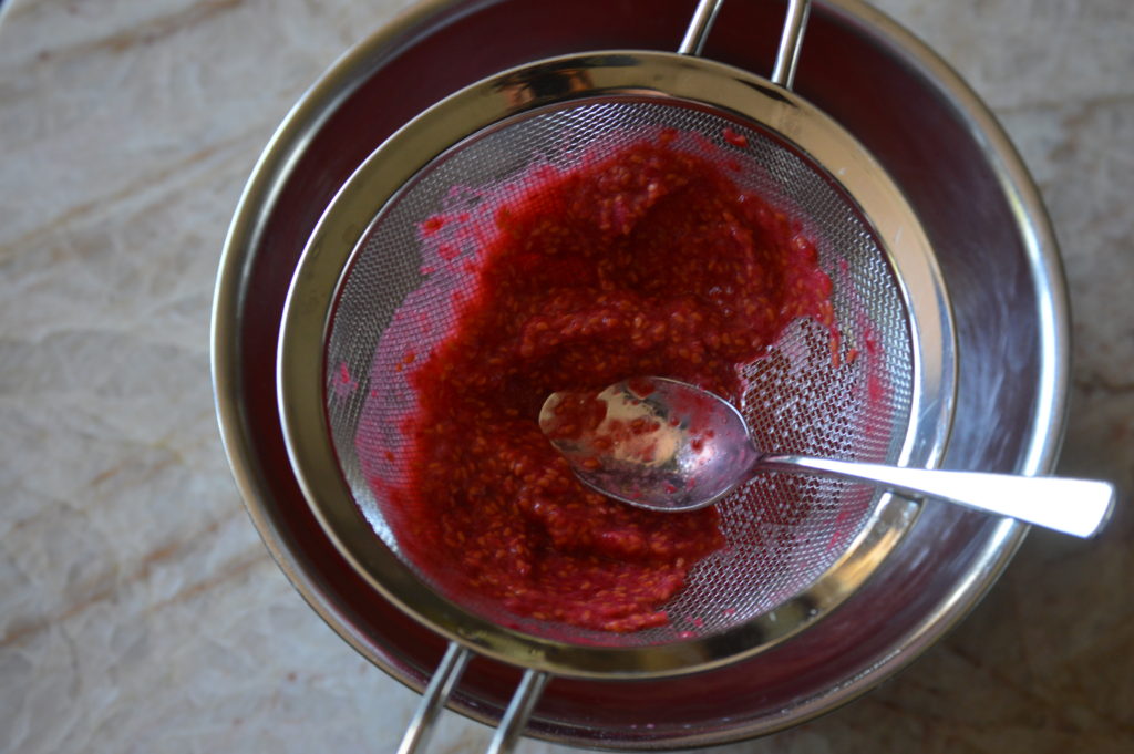 straining the raspberries through a fine mesh sieve