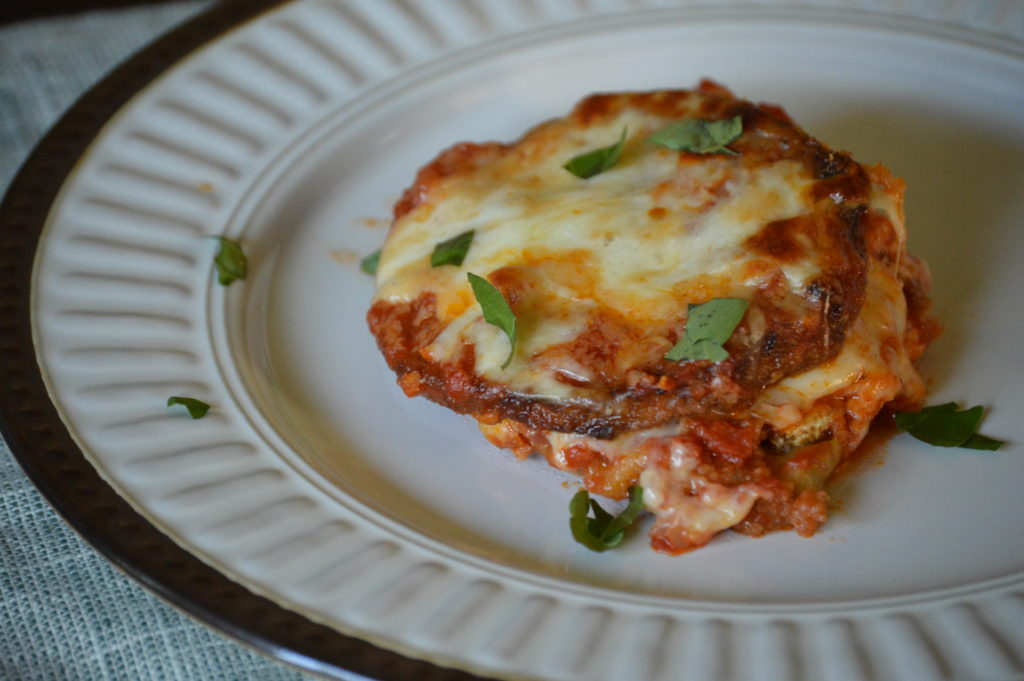 the finished eggplant parmesan on a plate with basil over top