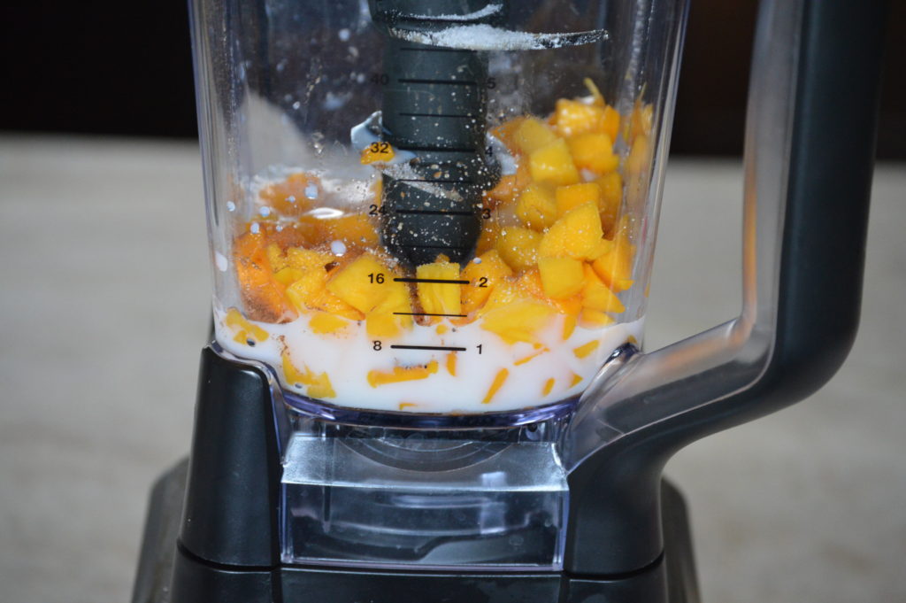 mango, milk, and spices added to a blender
