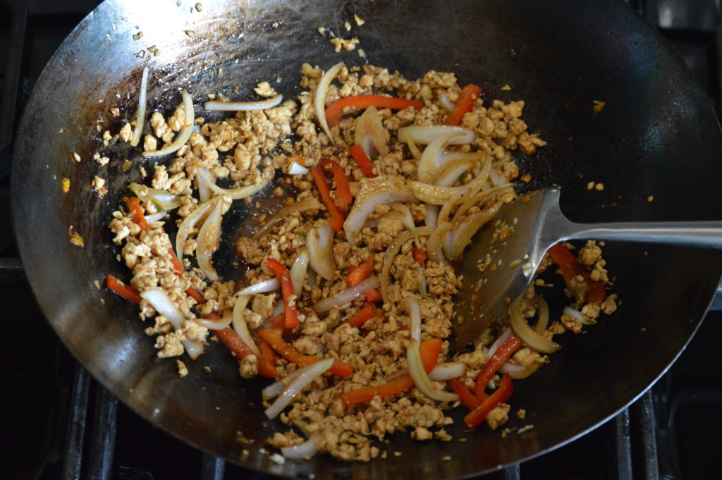 the onion, bell pepper, and sauce is added to the wok