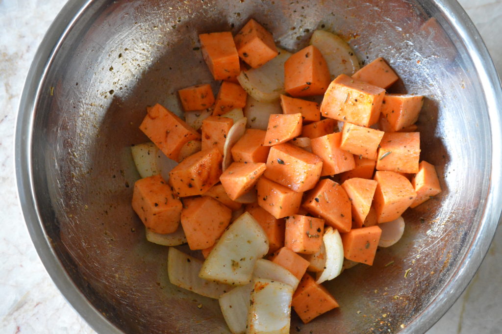 the sweet potato and onion are tossed in oil and spices