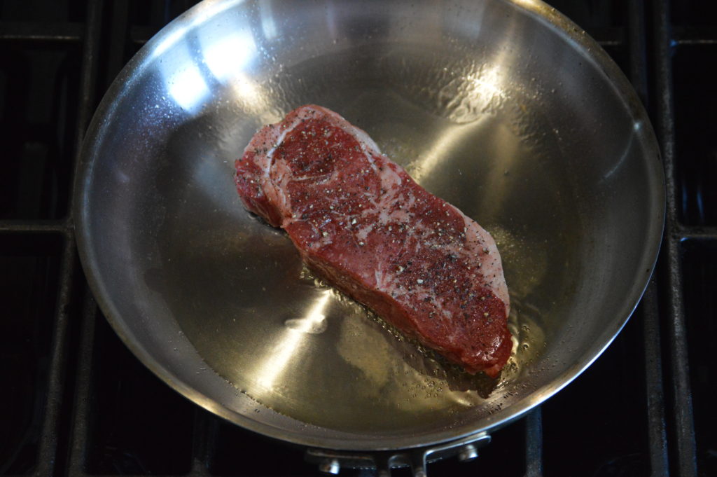 cooking the steak in a pan