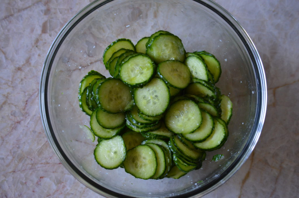 the sliced cucumbers are salted