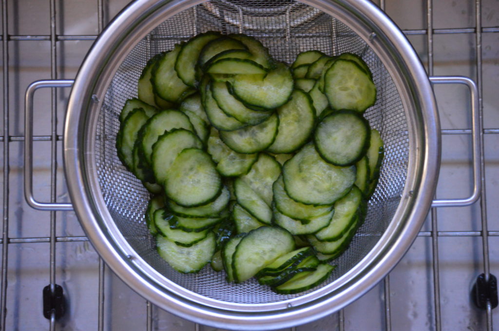 straining the liquid off of the cucumbers