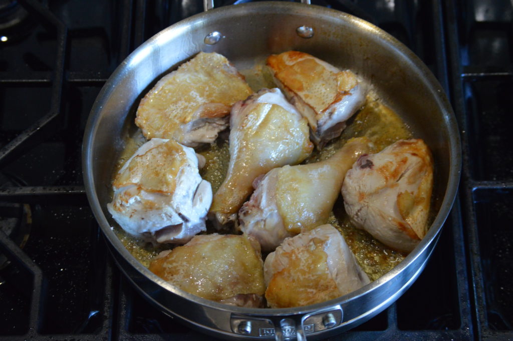 the chicken pieces are browned up in a pan