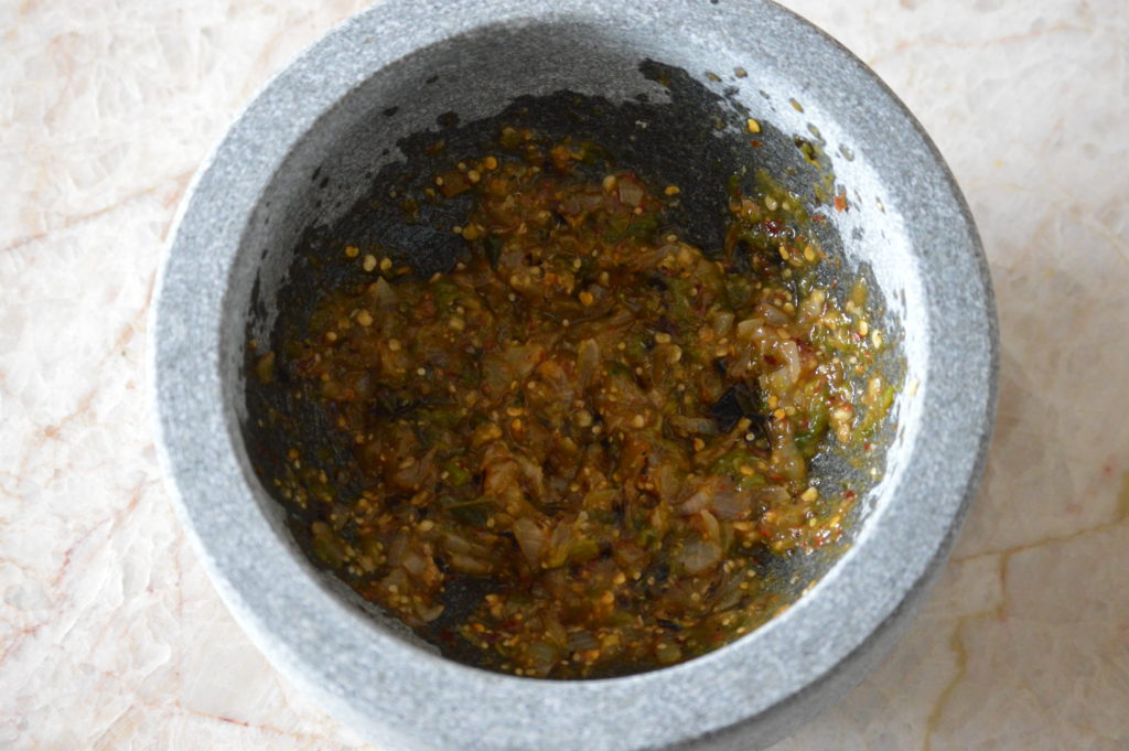 the tomatillo, jalapeno and onion are added to the molcajete