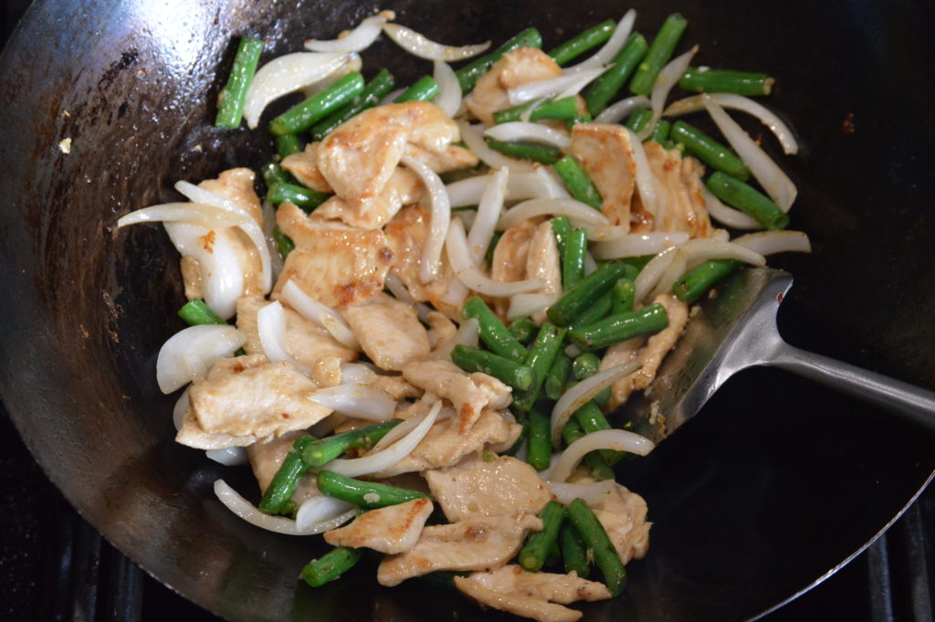 the chicken is added back to the wok