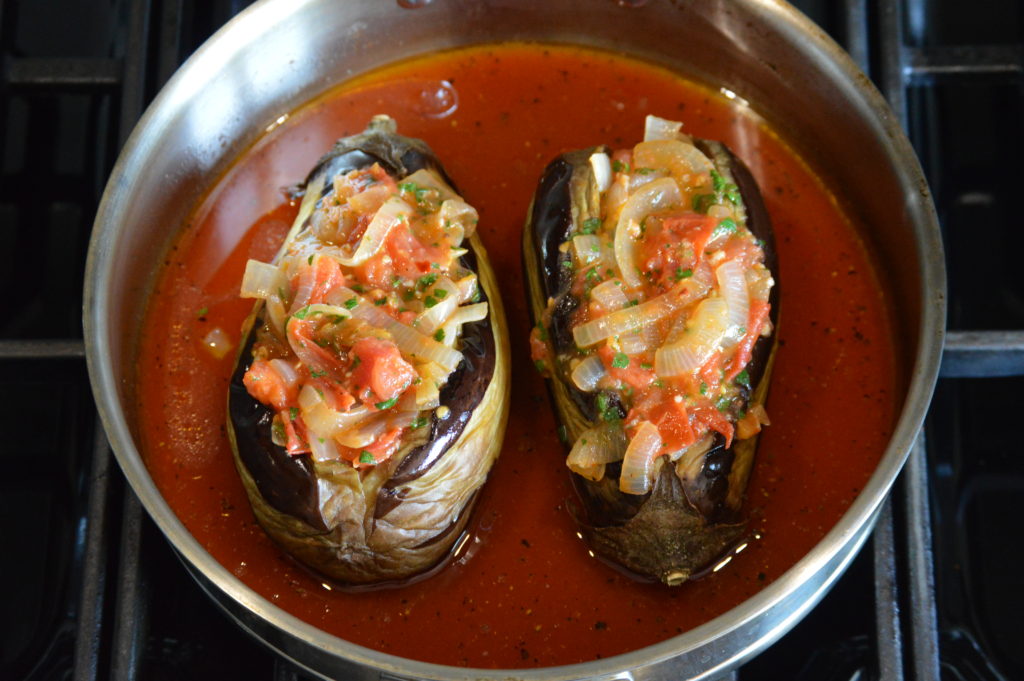 the stuffed eggplants are set in the pan with the sauce