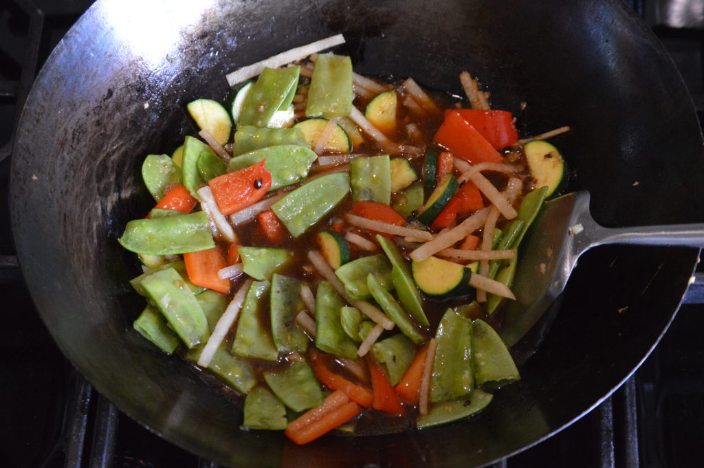 the snow peas and sauce are added to the wok