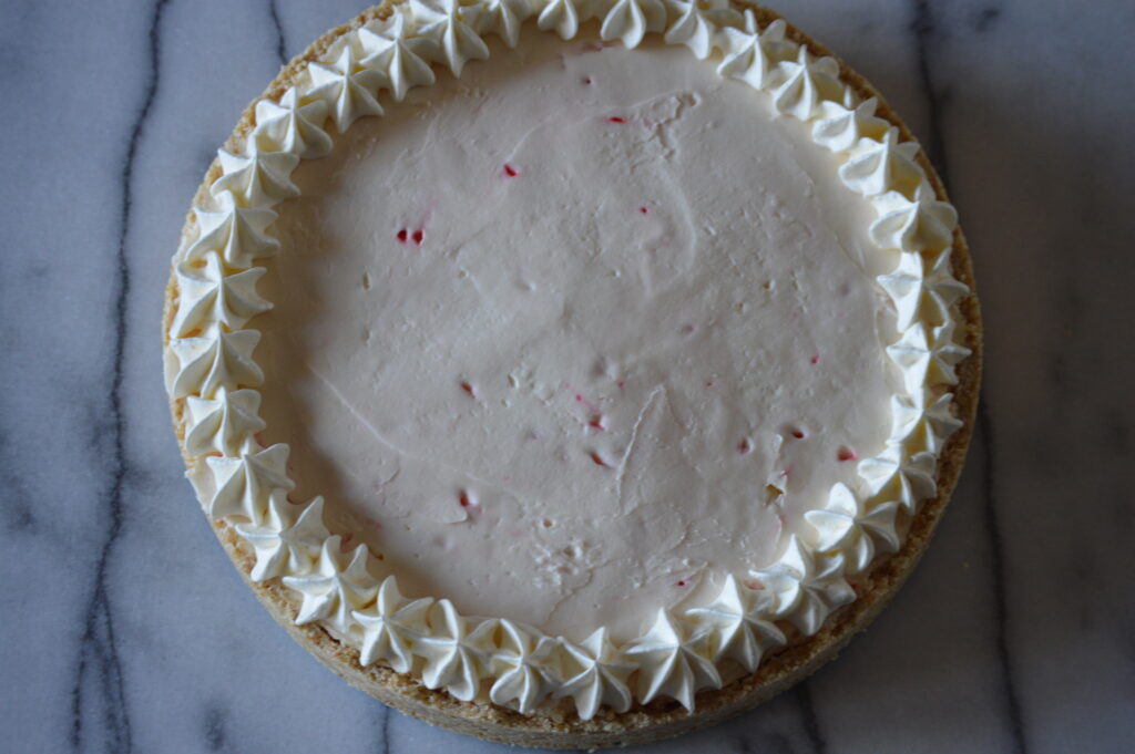 the peppermint white chocolate cheesecake is pipped with additional whipped cream on the edge