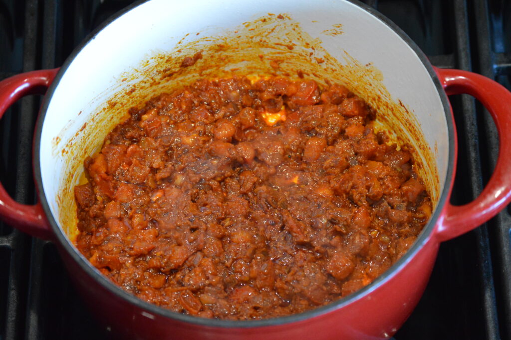 the aromatics, spices, and tomatoes are added