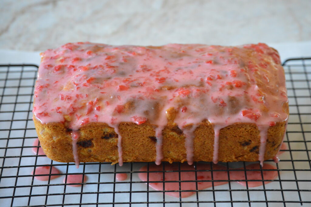 the glaze is spread over the top of the strawberry bread