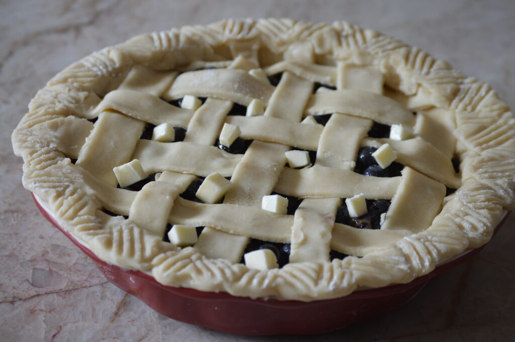 pieces of butter are added to the blueberry pie